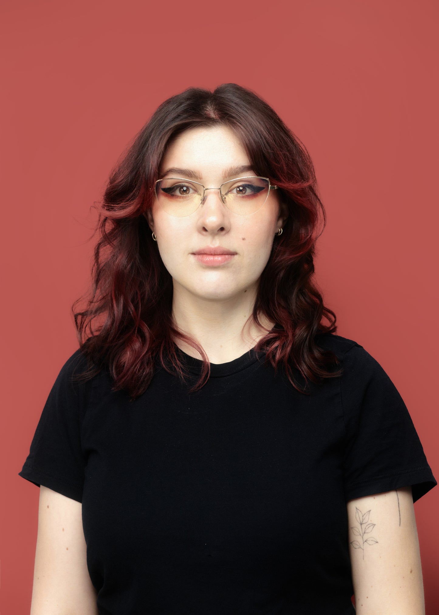 Person wearing glasses and a black shirt against a red background